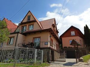 dom z płotem przed nim w obiekcie Apartament-studio, pokoje u Lucy w Rabce