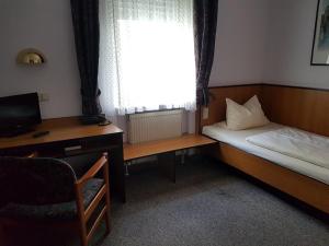 a bedroom with a bed and a desk and a window at Traube Hotel Oeffingen in Fellbach