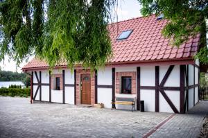 un edificio blanco con techo rojo y banco en Uroczysko Lutówko, en Sępólno Krajeńskie