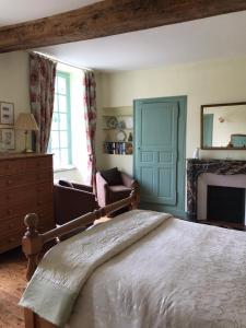 een slaapkamer met een bed en een stoel en een open haard bij Chambres d'Hôtes Belle Vallee in Domfront