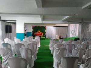 an empty room with white chairs and a green floor at Hotel BluRay in Belgaum