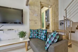 Charming Valletta 1 bedroom apartment off Republic Street sleeps 4 في فاليتا: غرفة معيشة مع أريكة وتلفزيون بشاشة مسطحة