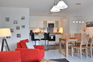 a living room and kitchen with a red couch and a table at Ferienwohnung Badestrand in Juliusruh