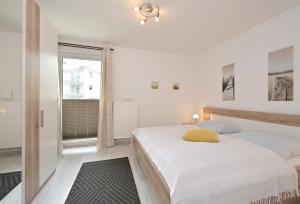 a white bedroom with two beds and a window at Ferienwohnung Badestrand in Juliusruh