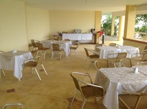 una habitación llena de mesas y sillas con manteles blancos en Setiba Pousada Park, en Guarapari