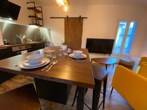 a dining room with a wooden table with dishes on it at Appartement de Standing au coeur de Libourne in Libourne