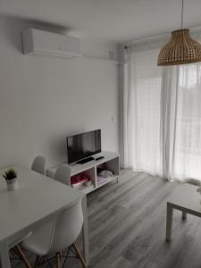 a white living room with a table and a tv at Apartamento Mare Nostrum Playa Arrabassada in Tarragona