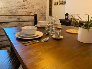 a wooden table with plates and bowls and glasses on it at Appartement de Standing au coeur de Libourne in Libourne