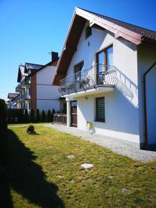 a white house with a balcony and a yard at Rivabell in Ostrowo
