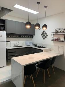 una cocina con una gran isla blanca con armarios negros en Gaudi Loft Design 50, en Campos do Jordão
