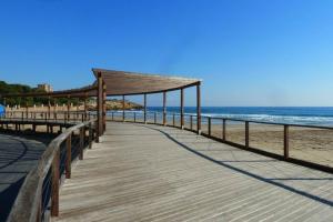 Apartamento Mare Nostrum Playa Arrabassada في تاراغونا: ممشى على الشاطئ مع المحيط في الخلفية