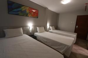 una habitación de hotel con 2 camas y un cuadro en la pared en Brasil Express, en Balneário Camboriú