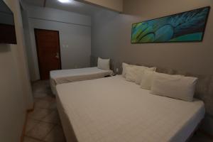 2 camas en una habitación de hotel con sábanas blancas en Brasil Express, en Balneário Camboriú