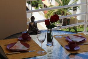 una mesa con rosas rojas y un jarrón de flores en Amoreira Mar IV Alvor, en Alvor
