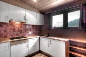 a kitchen with white cabinets and a sink and two windows at Apartments Bracun in Corvara in Badia