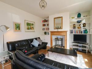 a living room with a black leather couch and a table at Cherry Lodge in Newark-on-Trent