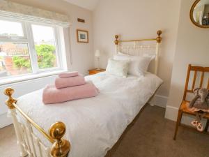 a bedroom with a bed with a pink towel on it at Bennett's Cottage in Oakham