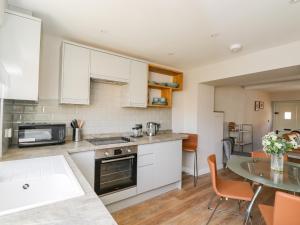 a kitchen with white cabinets and a table at Troopers Cottage in Frome