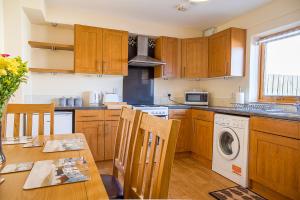 a kitchen with wooden cabinets and a table with a washing machine at Modern 2 bedroom garden flat in Inverness
