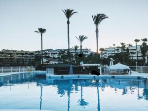 a large swimming pool with palm trees in the background at Golf Coast Los Alamos, Primera Linea de Playa in Torremolinos