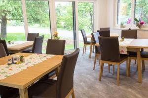 a dining room with tables and chairs and windows at Pension Puster in Gobernitz