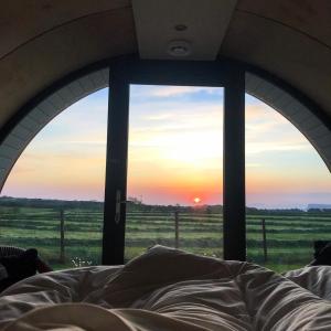 a bed in a room with a view of a sunset at Black Knowe, Luxury Glamping Pods, Ballycastle in Ballycastle