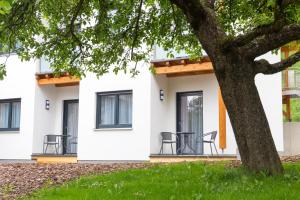 a white building with black chairs and a tree at Pension Puster in Gobernitz