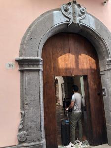 a man with a suitcase entering a wooden door at Maison De Lucia in Meta