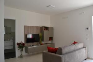 un salon avec un canapé et une télévision dans l'établissement Il Tramonto Apartment - Villaggio di Mary, à Locorotondo