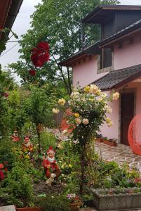 einen Garten mit Blumen und Figuren vor einem Haus in der Unterkunft Pensiunea Happy Flowers in Greci