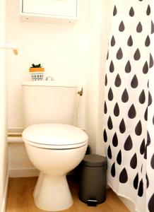 a white toilet in a bathroom with a black and white shower curtain at Appart Hôtel Futuroscope Nintendo - site du Futuroscope - Poitiers in Jaunay-Marigny