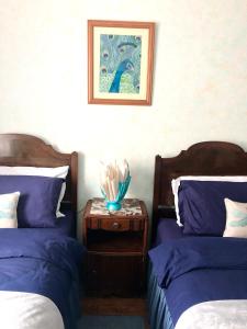 a bedroom with two beds and a table with a picture at Le Figuier in La Forêt-Auvray
