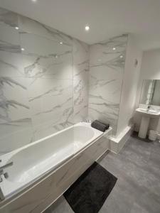 a white bathroom with a tub and a sink at High Street Stylish City Centre Apartment, 2 Bed in Perth