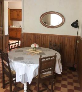 a dining room with a table and a mirror at Le Figuier in La Forêt-Auvray