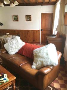 a brown leather couch with white pillows on it at Le Figuier in La Forêt-Auvray