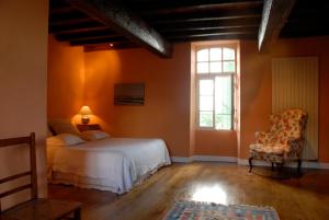 1 dormitorio con 1 cama, 1 silla y 1 ventana en Chambres d'Hôtes La Bastide des Trémières, en Saint-Antoine-de-Breuilh