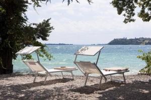 twee stoelen op een strand bij het water bij Villa Ondina - Wonderful villa with private beach and big garden in Salò