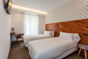 a hotel room with two beds and a desk at Mar do Ézaro - Boutique Hotel in Ézaro +59 photos