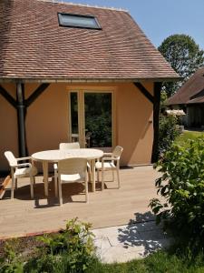 una terraza de madera con mesa y sillas en una casa en Gîte Les Bauvans, en Presly