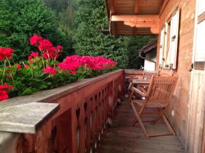 a wooden balcony with a chair and flowers at Blockhaus-Traum Huber in Garmisch-Partenkirchen