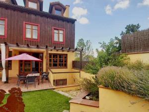 ein Haus mit einer Terrasse mit einem Tisch und einem Sonnenschirm in der Unterkunft La Querencia de Valsaín in La Pradera de Navalhorno