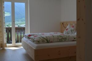a bed in a room with a view of a balcony at Haus Talblick "Neuräutl" Ferienwohnung 2 in Naturno