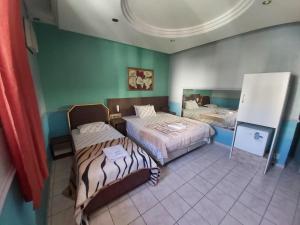 2 Betten in einem Zimmer mit grünen Wänden in der Unterkunft Hotel Puma in São Paulo