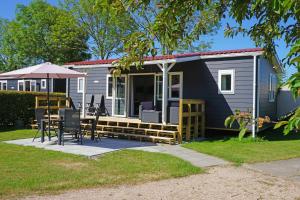 a tiny house with a patio and an umbrella at Minicamping In de Bocht in Grijpskerke