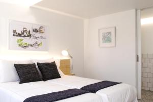 Dormitorio blanco con cama blanca y almohadas negras en Margueda, en Alcains