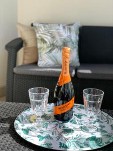 a bottle of wine on a plate with two glasses at Apartament Jantarowe Zacisze Rose in Jantar