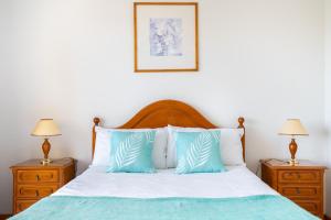 Un dormitorio con una cama con almohadas azules y blancas. en Jardins da Rocha BeachView by Encantos do Algarve 19A, en Portimão