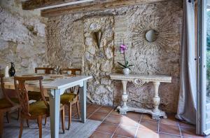 comedor con mesa y pared de piedra en Casa Olivo at Masia Nur Sitges, Adults only, en Canyelles