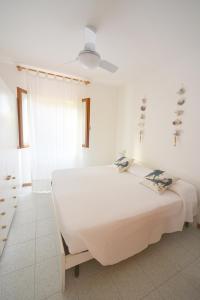 a white bedroom with a bed and a ceiling fan at Case vacanza Barbatoja in Fetovaia