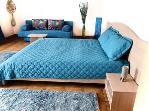 a bedroom with a blue bed and a couch at Vila Adriana in Eforie Nord